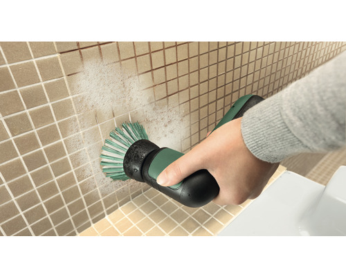 O persoană curăță faianța cu o perie electrică de curățare