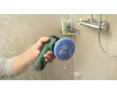 O persoană curăță un perete de duș cu o perie electrică de curățare.