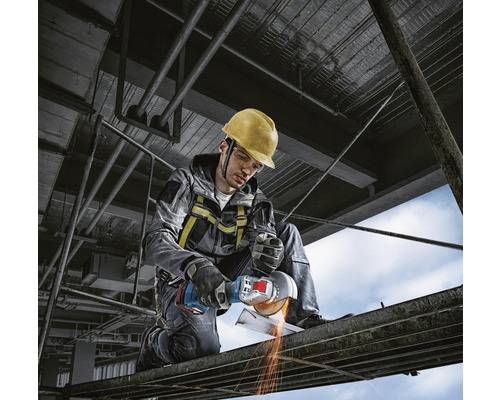 Muncitor cu cască de protecție și polizor unghiular tăind metal pe un șantier