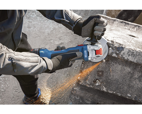 O persoană folosește un polizor unghiular cu acumulator pentru a tăia beton.