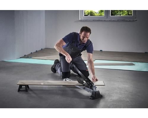 Bărbat taie laminatul cu un tăietor de laminat.