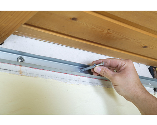 Instalarea unei șine metalice cu diblu și șurub pe un perete