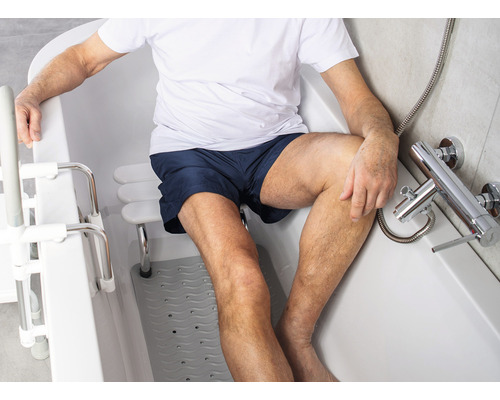 Bărbat șezând într-o cadă cu ajutor pentru intrare și scaun de baie