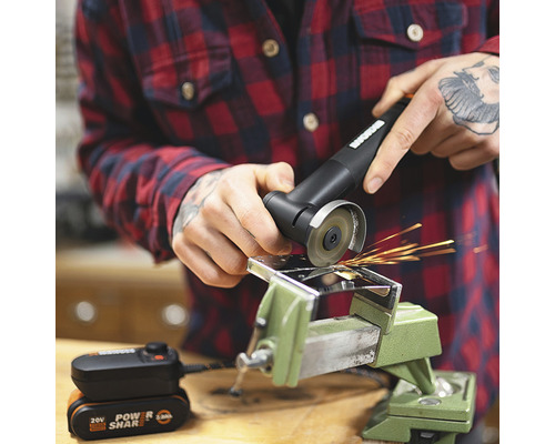 O persoană folosește un polizor unghiular cu acumulator pe o piesă de lucru fixată într-o menghină.