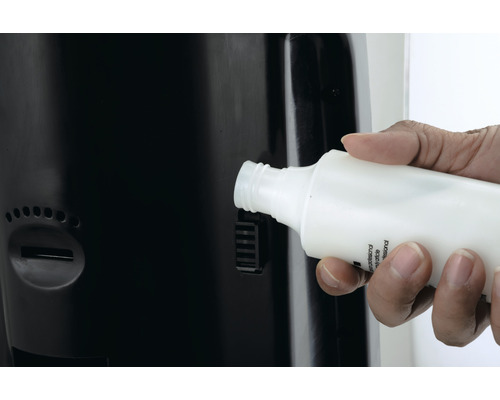 O mână introduce o sticlă într-un dozator.