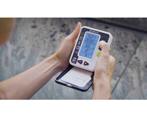 O persoană ține și operează un controler de irigare Geka în mâini.