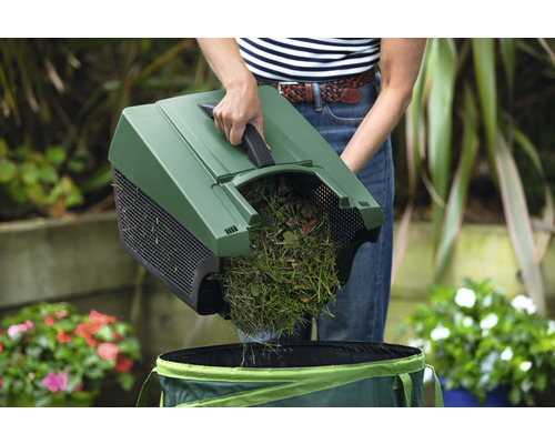 Persoană care varsă iarbă și frunze cu o măturătoare într-un sac de grădină