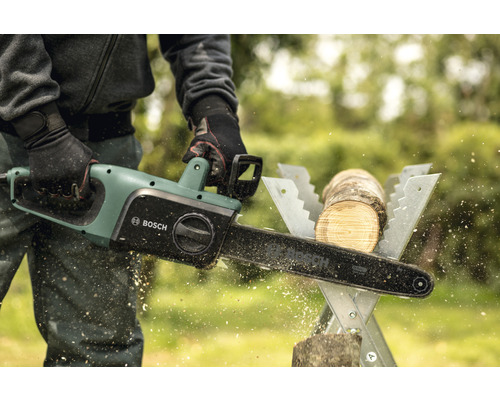 Bărbat taie o bucată de lemn cu un lanț electric Bosch pe un capră de tăiere