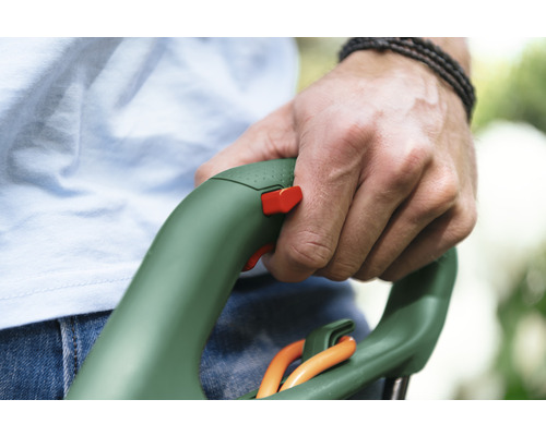 Mână ținând un trimmer de gazon cu comutator de siguranță