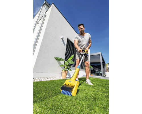 Un bărbat folosește o perie pentru rosturi în grădină