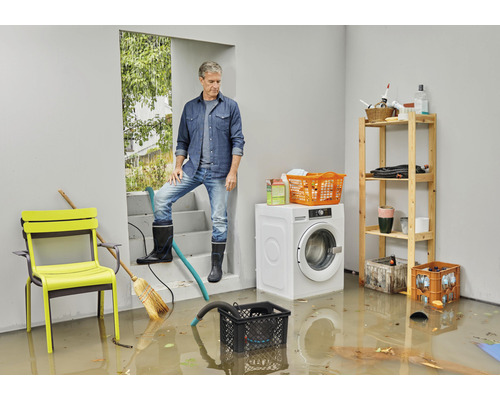 Subsol inundat cu un bărbat pe scări, mașină de spălat și rafturi