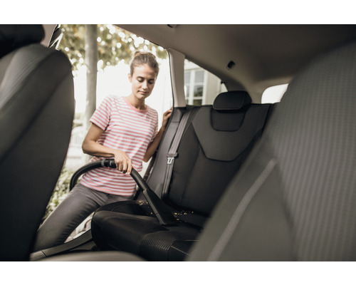 Femeie aspiră scaunele auto cu un aspirator.