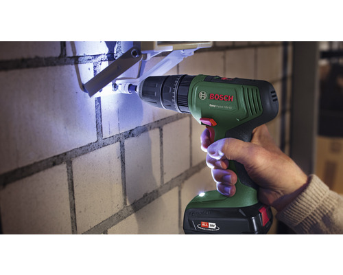 O persoană găurește un perete de cărămidă cu o șurubelniță cu impact cu acumulator Bosch.