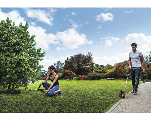 Scenă de grădină cu mașini de tuns iarba lucrând în grădină.