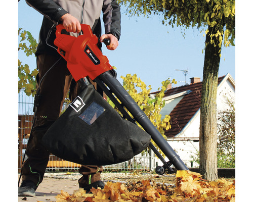 O persoană folosește un aspirator de frunze Einhell pentru a aspira frunzele din grădină.