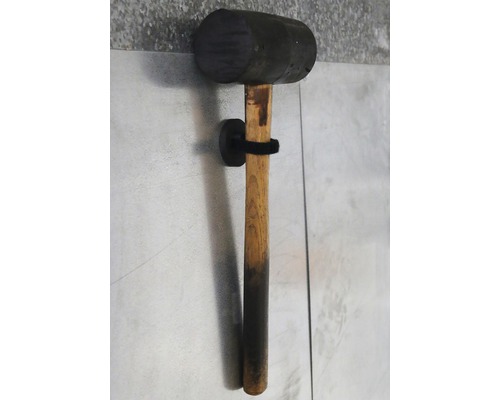 Ciocan de cauciuc cu mâner de lemn pe un suport de perete