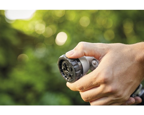 Mână ținând capul de pulverizare al furtunului de grădină