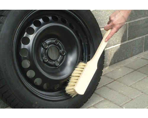 Jantă de oțel cu anvelopă de iarnă curățată cu o perie.