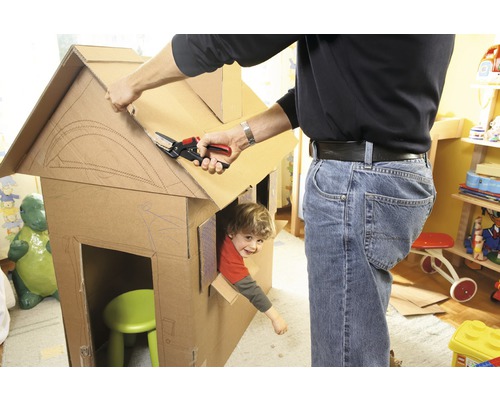 Bărbat care taie cu foarfeca o casă de carton cu un copil