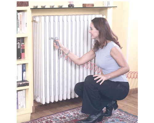 Femeie curățând caloriferul cu un pistol cu aer comprimat