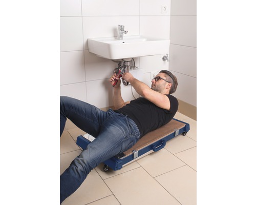 Instalator pe o placă de montaj reparând o chiuvetă