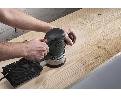 O persoană șlefuiește o scândură de lemn cu o șlefuitoare excentrică.