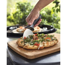 O pizza este tăiată cu un tăietor de pizza pe un tocător.