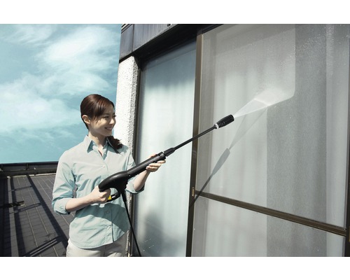 Femeie curăță geamuri cu un aparat de curățat cu înaltă presiune