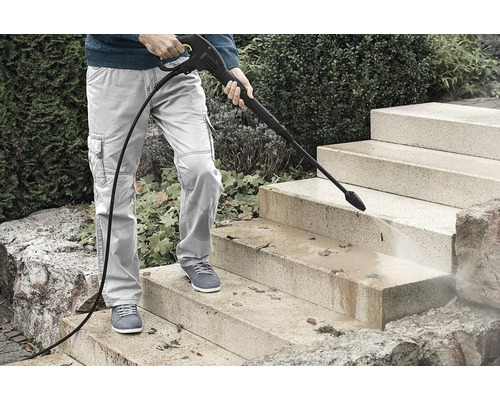 Persoană care curăță scări de piatră cu un curățător cu presiune