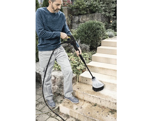 O persoană curăță o scară exterioară cu un curățător cu presiune.