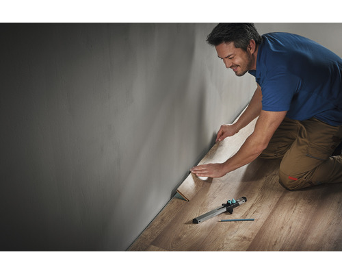 Bărbat care așază laminat cu scule de-a lungul unui perete