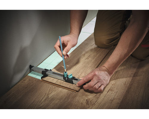 O persoană marchează laminatul cu un creion și un instrument de marcare pentru laminat