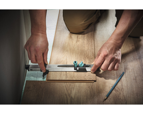 Persoană care folosește un instrument de măsură pentru a măsura o bucată de laminat