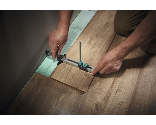 Dulgher care pune parchet laminat cu o unealtă de zgâriere