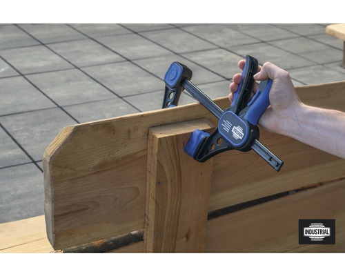 Persoană care folosește un clește cu o singură mână pentru a lipi lemn