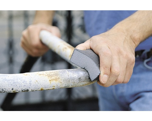 O persoană șlefuiește o țeavă metalică cu un bloc de șlefuit