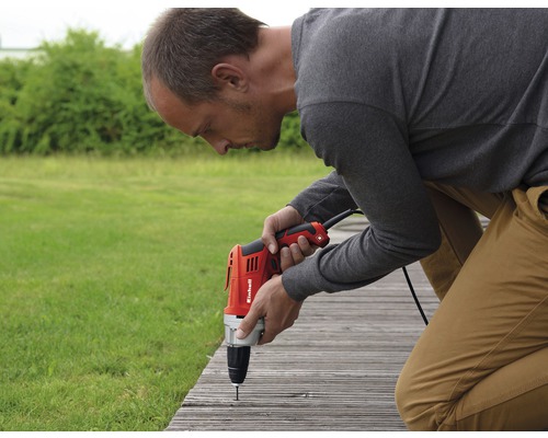 Un bărbat fixează o scândură cu o mașină de găurit