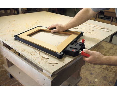 Rama din lemn este fixată cu o menghină de ramă pe un banc de lucru.