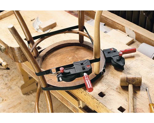 Un scaun de lemn este reparat cu un întinzător cu bandă pe un banc de lucru