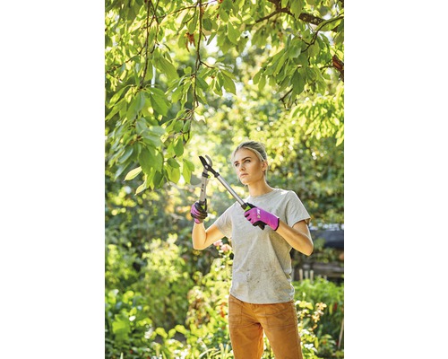 Femeie tăind crengi cu un foarfece de grădină