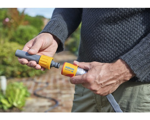 O persoană conectează un furtun de grădină la un conector de furtun.