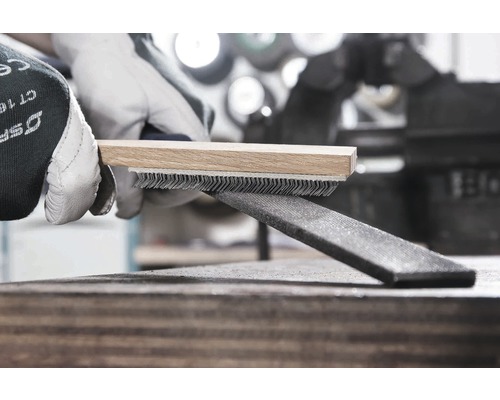 Perie de sârmă cu mâner de lemn curăță o pilă de metal