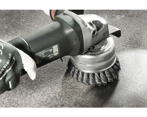 Accesoriu perie de sârmă pe o mașină de șlefuit în timpul curățării unei suprafețe