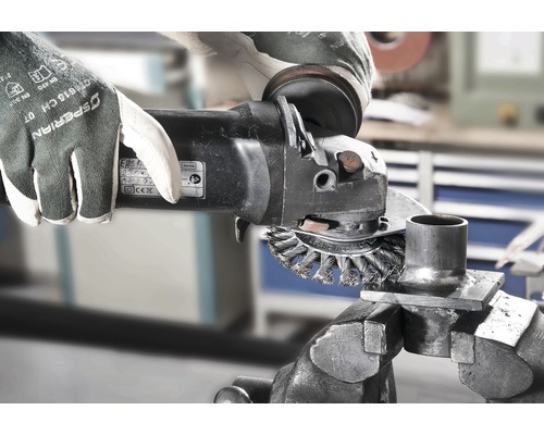 O persoană folosește o perie de sârmă pe un polizor unghiular pentru a curăța o piesă metalică fixată într-o menghină.