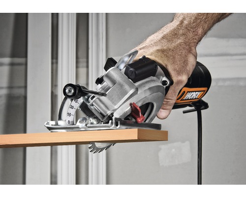 Mână care folosește un ferăstrău circular manual Worx pentru a tăia o bucată de lemn