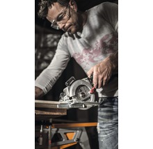Bărbat taie o scândură de lemn cu un fierăstrău circular manual pe un banc de lucru