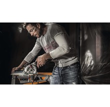 Un bărbat lucrează cu un ferăstrău circular portabil la o piesă de prelucrat pe o masă de lucru marca Worx.