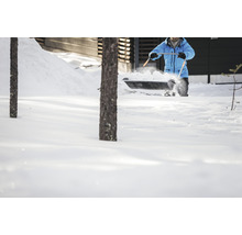 O persoană curăță zăpada cu o lopată de zăpadă în fața unei case.