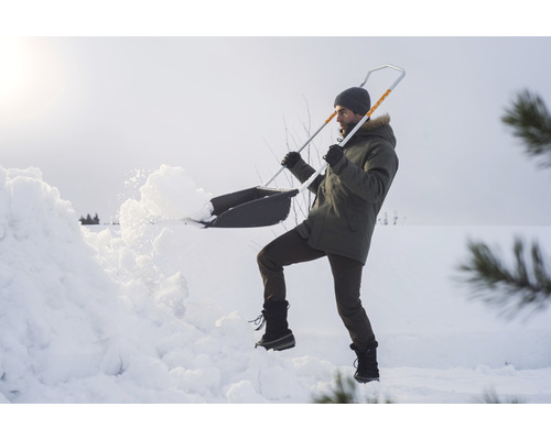 O persoană îndepărtează zăpada cu o lopată de zăpadă.