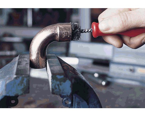 Peria de țevi curăță o țeavă de cupru într-o menghină